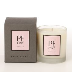 a candle that is next to a box on a white surface with the words pe on it