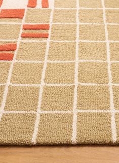 a brown and white rug with orange squares on the bottom, in front of a wooden floor