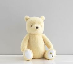 a yellow teddy bear sitting on top of a white table next to a gray wall