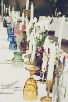 a long table with candles and vases on top of it, all lined up