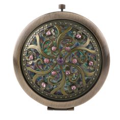 an antique looking pocket watch with multicolored stones in the center and filigrees on the outside