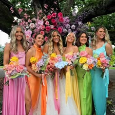 a group of women standing next to each other in dresses and holding bouquets with flowers on them