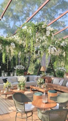 an outdoor seating area with wicker furniture and flowers hanging from the pergolated roof