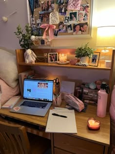 a laptop computer sitting on top of a wooden desk next to a lamp and pictures