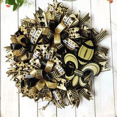 a black and gold new orleans saints wreath on a white wooden surface with flowers in the background