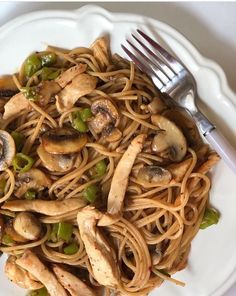 a white plate topped with pasta covered in mushrooms and green peppers next to a fork