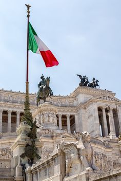 an italian flag flying in front of a building with statues on the sides and columns