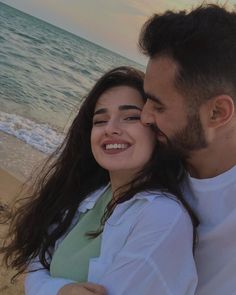 a man and woman hugging on the beach