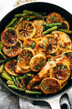 chicken, asparagus and oranges in a skillet with lemon slices on top