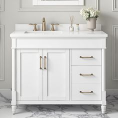 a white bathroom vanity with two sinks and gold faucets on the counter top