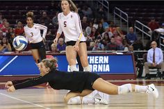 a volleyball player dives to catch the ball