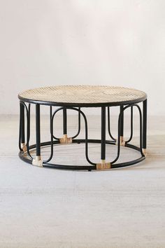 a round coffee table with black metal frame and wicker top, on a white background