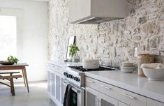 a kitchen with stone walls and white cabinets