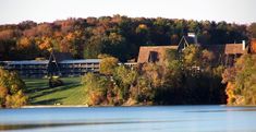 a large building sitting on top of a lush green hillside next to a lake