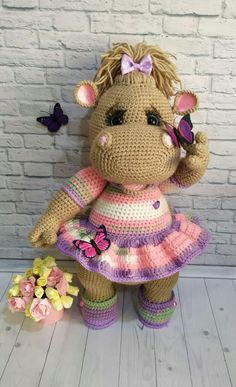 a crocheted teddy bear dressed in a dress with butterflies on its nose and head