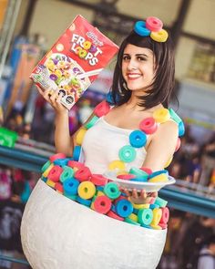 a woman in a costume holding a book and some doughnuts on her head