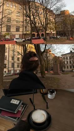 a woman sitting at a table with a cup of coffee in front of some buildings