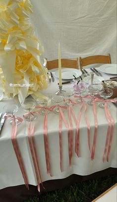 the table is set up with pink and white ribbons on it, along with silverware