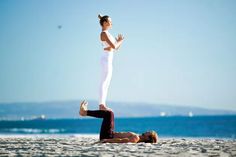 a man and woman doing yoga on the beach