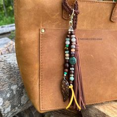 a tasseled leather bag charm with beads and stones on it sitting on a rock