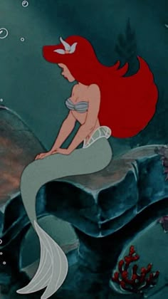 the little mermaid is sitting on top of a rock and looking at something in the water