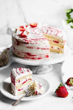 two slices of cake on plates with strawberries next to it and one slice missing