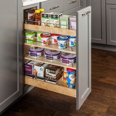 the pull out spice rack in this kitchen is full of spices and canned food items