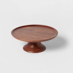 a wooden cake plate sitting on top of a white surface with no one around it