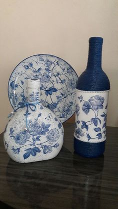 a blue and white vase sitting next to a bottle on top of a wooden table