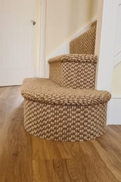 a basket sitting on top of a wooden floor next to a stair case in a house