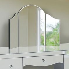 a white dressing table with mirror and drawers