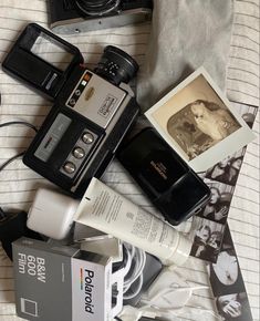 an old camera and other items are laying on the bed next to it's contents