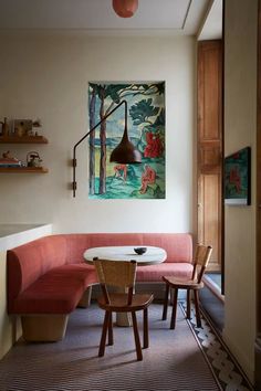 a painting hangs on the wall next to a table and chairs