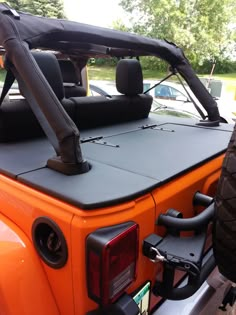 an orange jeep is parked on the side of the road with it's roof up