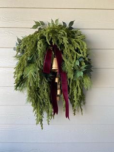 a wreath hanging on the side of a building with bells and greenery around it