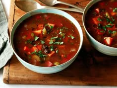 two bowls of vegetable soup on a cutting board