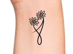 a woman's arm with a tattoo on it that has daisies in the shape of a heart