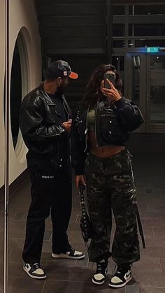 a man and woman standing next to each other in front of a mirror taking pictures