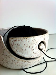 a white and brown bowl with black string in the middle on top of a table