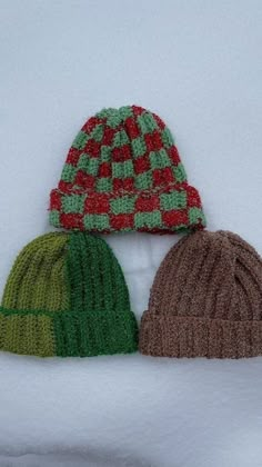 three knitted hats sitting on top of snow covered ground