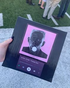 a person holding up a photo with an ad on it's face in front of a group of people