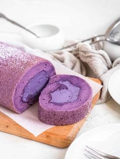 a purple cake sitting on top of a wooden cutting board