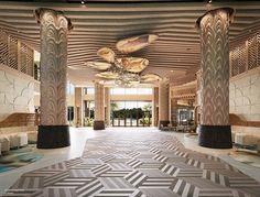 the lobby is decorated in art deco style with columns and chandeliers hanging from the ceiling