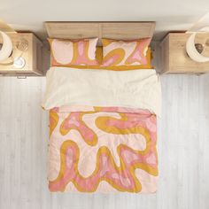 an overhead view of a bed with pink and yellow comforters on top of it