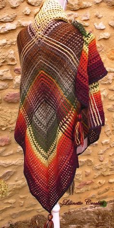 a woman's shawl on display in front of a stone wall