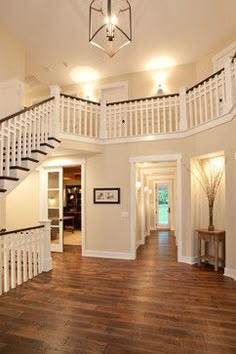 the inside of a house with wood floors and white railings on the second floor