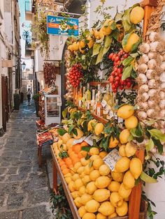 a fruit stand with lemons, oranges and other fruits on display in an alleyway