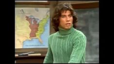 the young man is wearing a green turtle neck sweater