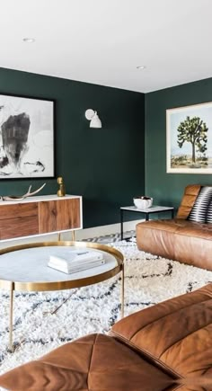 a living room with green walls and leather furniture in the center, along with a painting on the wall