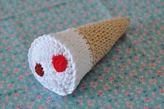 an ice cream cone with red and white crochet on it sitting on a table